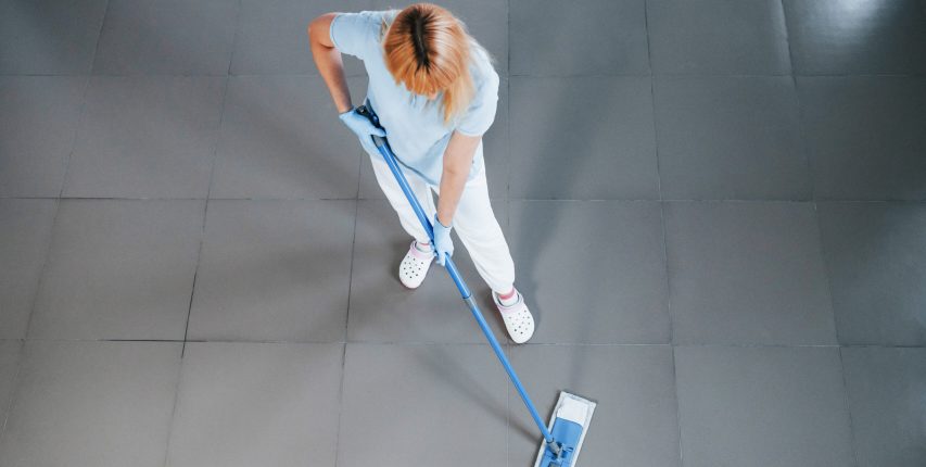 Top view of woman in blue shirt and protective gloves that uses vacuum cleaner Top view of woman in blue shirt and protective gloves that uses vacuum cleaner.